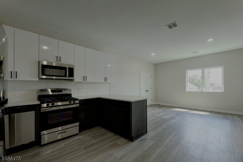 a kitchen with granite countertop white cabinets and black appliances