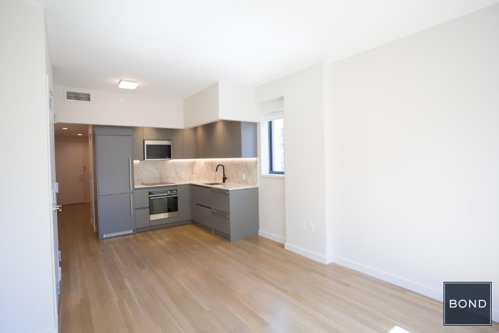 a large kitchen with stainless steel appliances a large counter top and a refrigerator