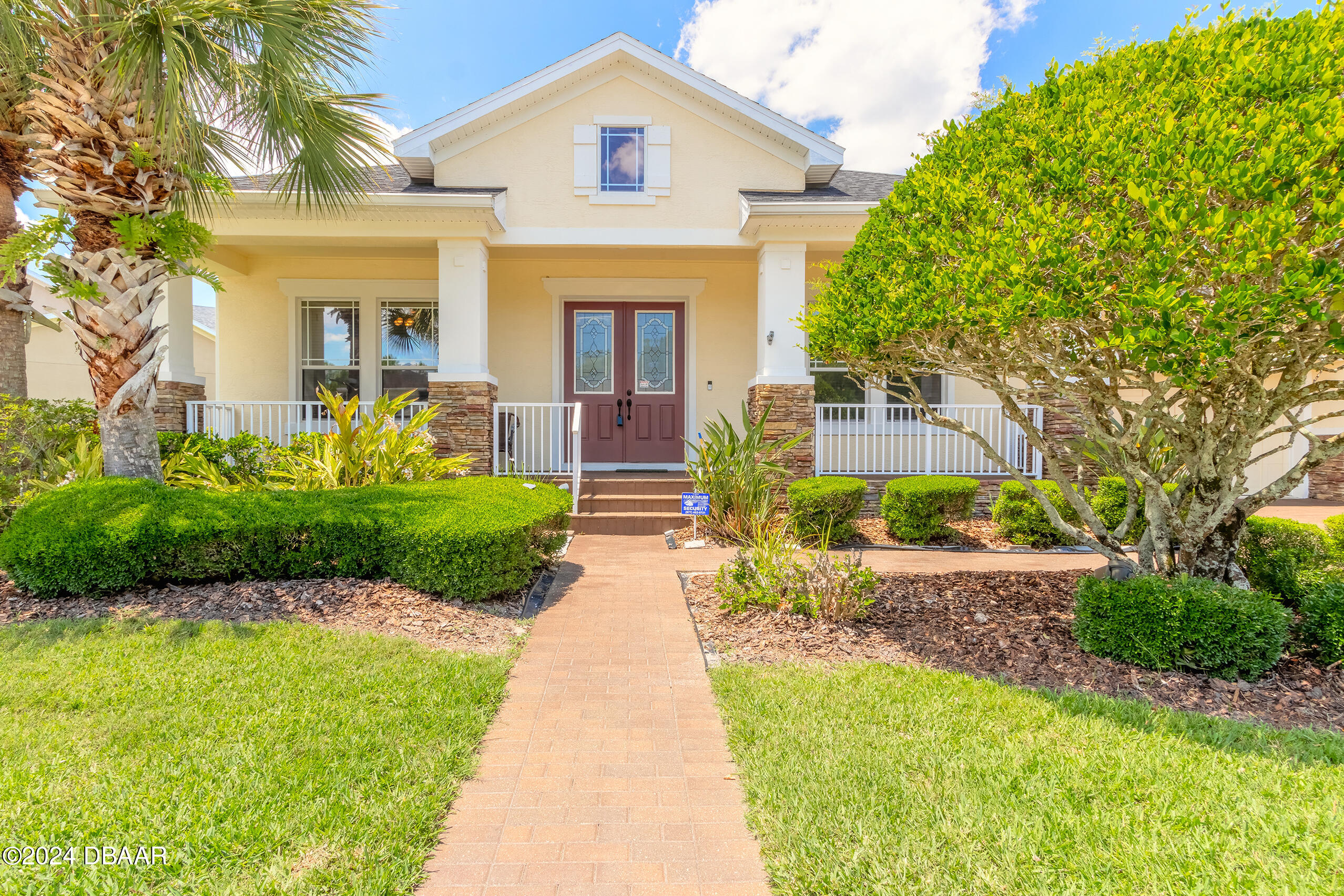 a front view of a house with a yard and potted plants