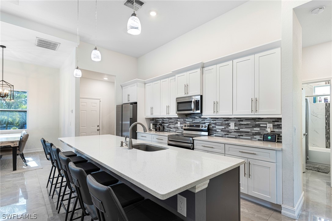 a kitchen with stainless steel appliances a stove a sink a dining table and chairs