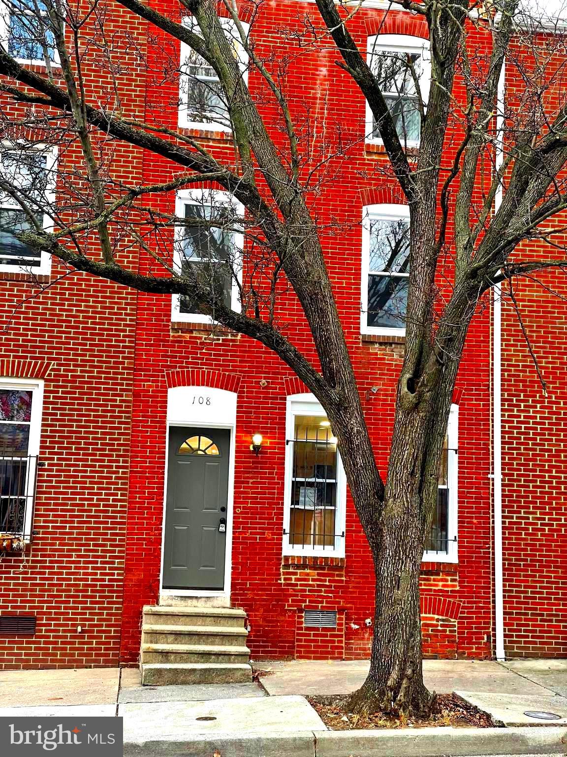 a front view of a house with a tree