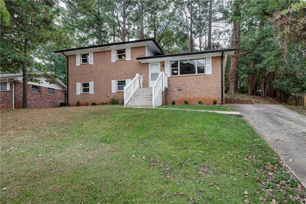 a front view of house with yard and trees in the background