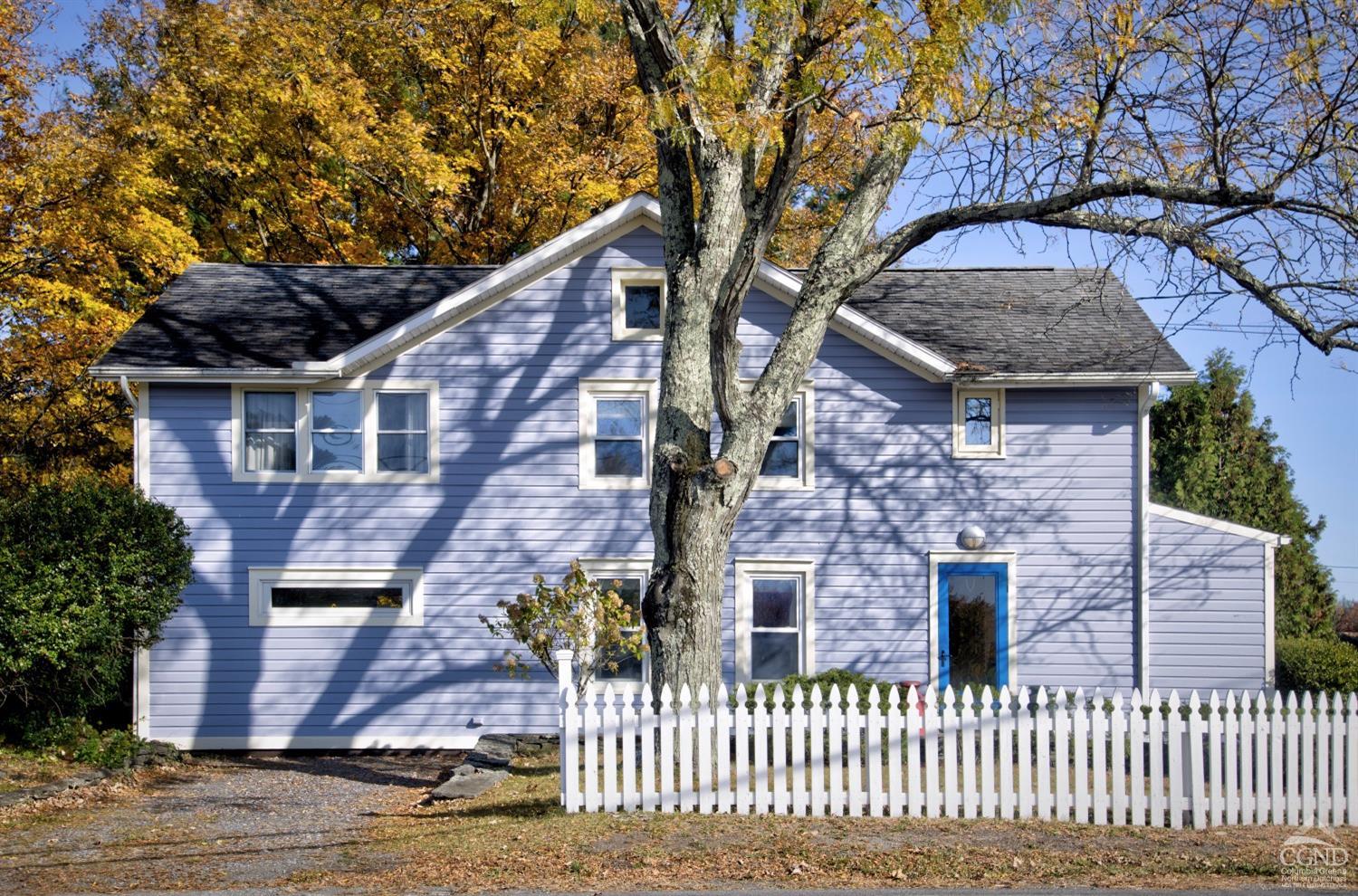 a front view of a house with a tree