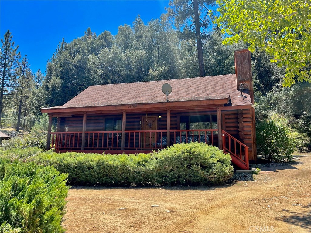 a view of a house that has a small yard and large trees