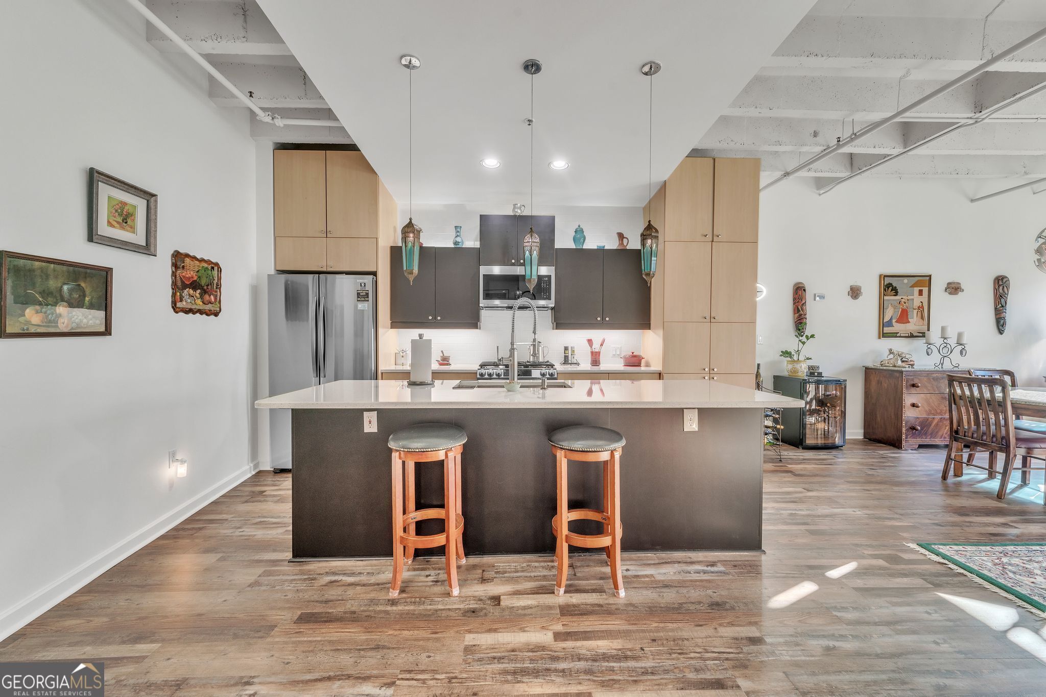 a kitchen with stainless steel appliances kitchen island granite countertop a table chairs sink and cabinets