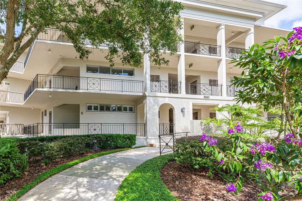 a front view of a multi story residential apartment building with yard and sign board