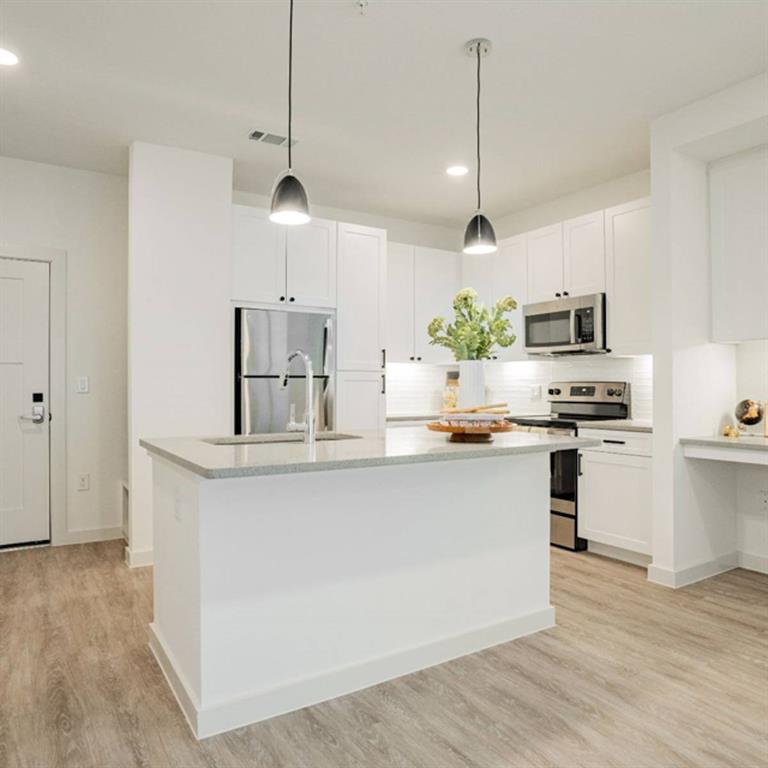 a kitchen with kitchen island white cabinets and stainless steel appliances