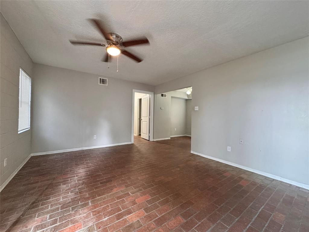 a view of an empty room and chandelier fan