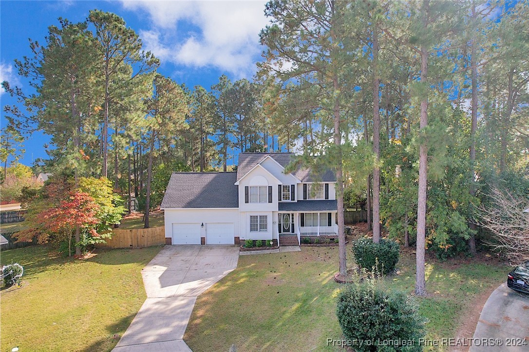 a front view of a house with a yard and large trees