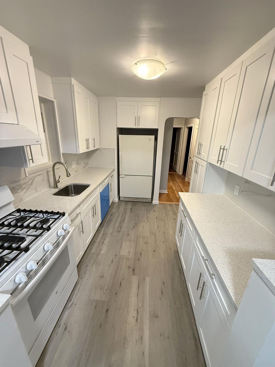 Kitchen featuring white cabinets, white appliances, sink, and light hardwood / wood-style flooring