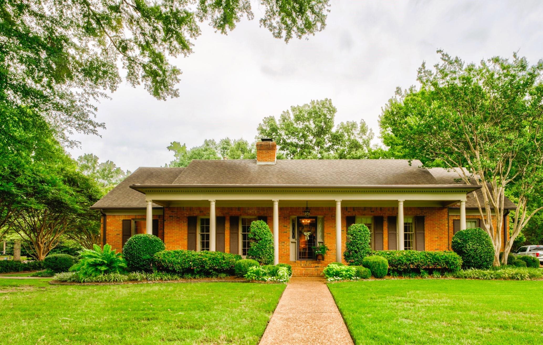 a front view of a house with a yard and potted plants