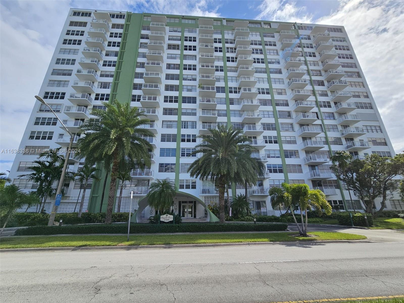 a front view of a multi story building with yard and green space