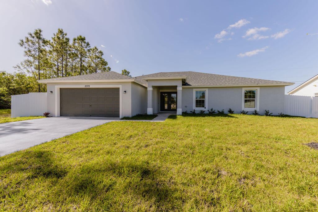 a front view of house with yard and trees in the background