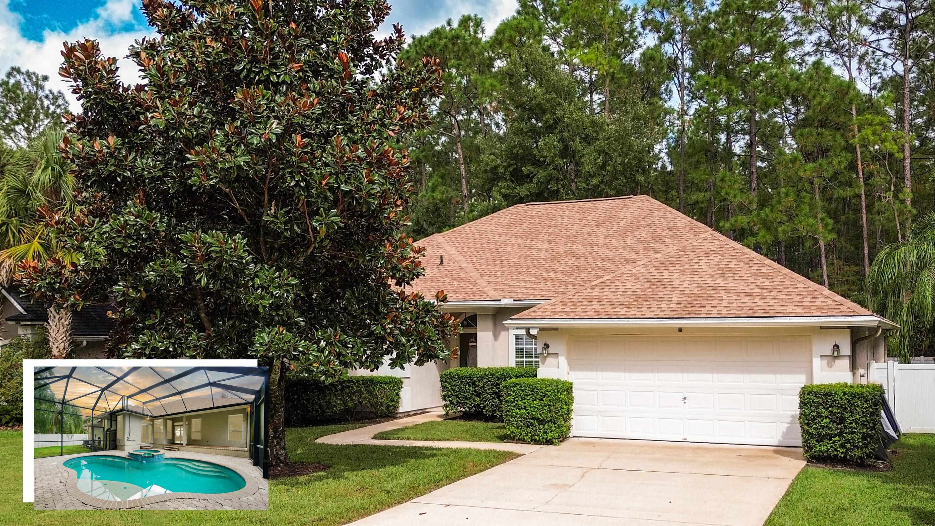 a view of a house with a yard plants and large tree