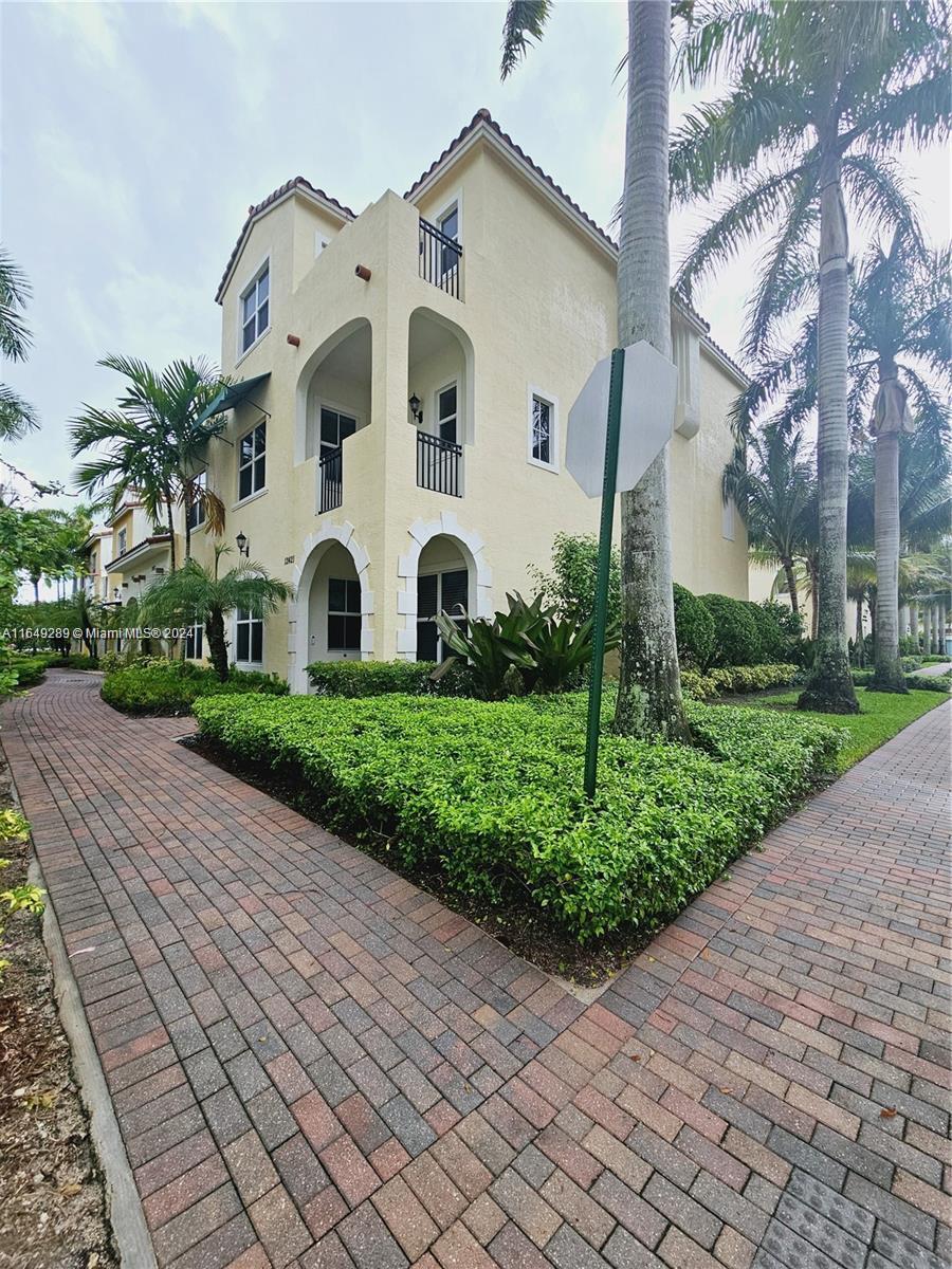 a front view of a white house with a yard and potted plants