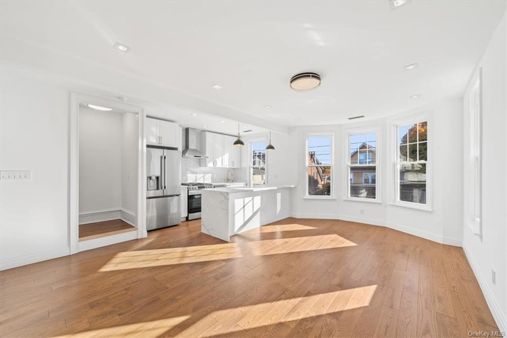 a view of a kitchen with refrigerator and wooden floor