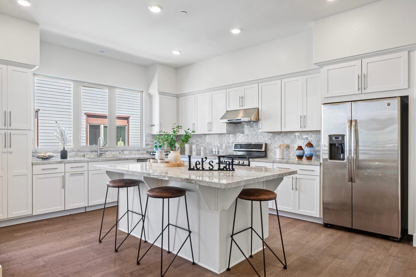 a kitchen with refrigerator a stove a sink and white cabinets with wooden floor