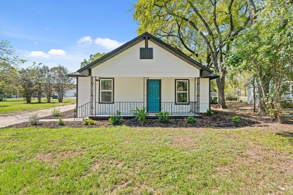 a front view of house with yard and trees in the background