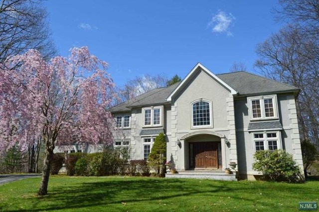 a front view of a house with a garden and trees