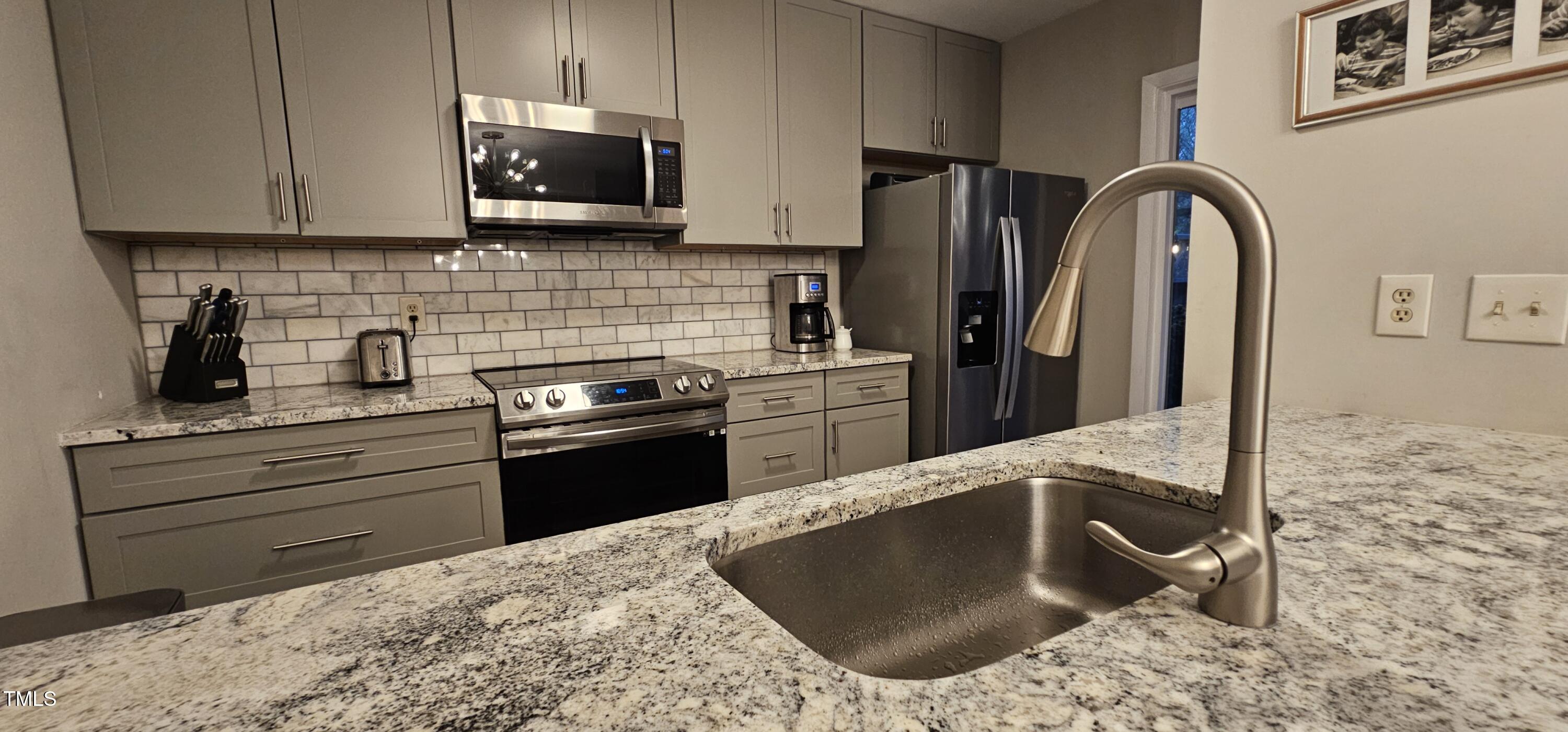 a kitchen with stainless steel appliances granite countertop a stove a sink and a microwave