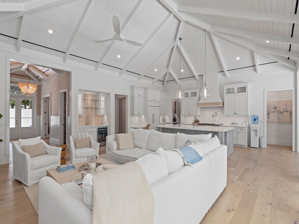 a living room with white couches and white cabinets with wooden floor