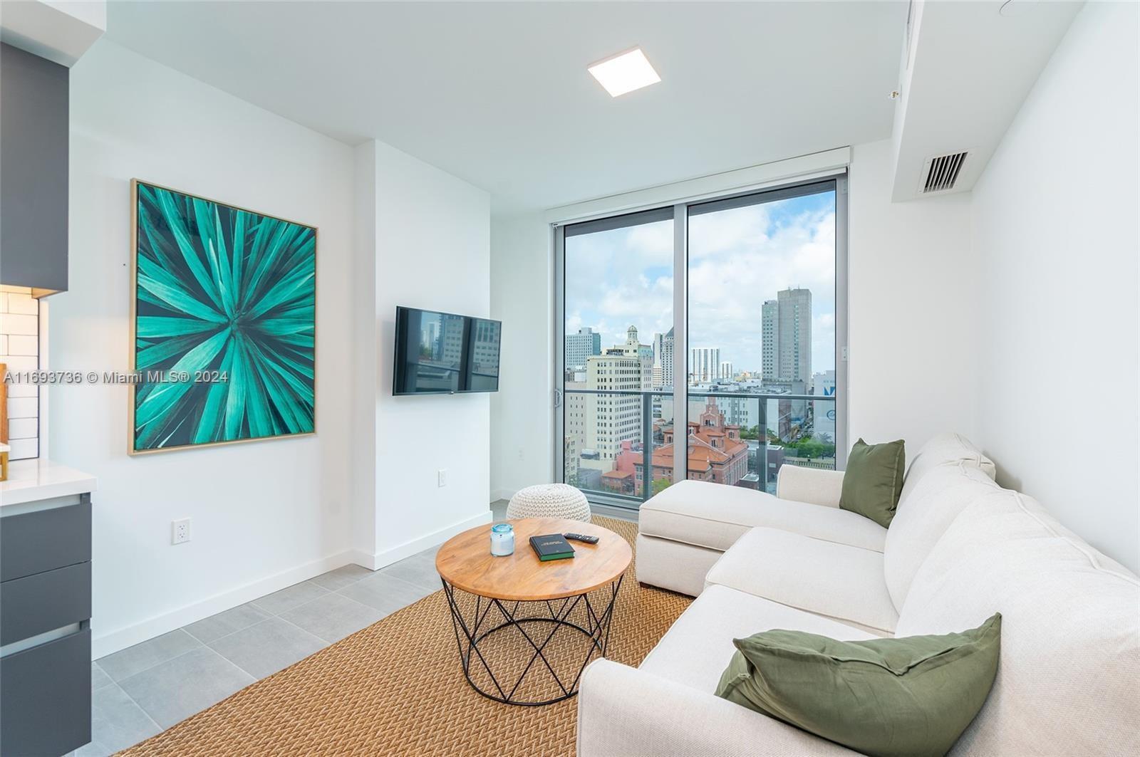 a living room with furniture a flat screen tv and a large window