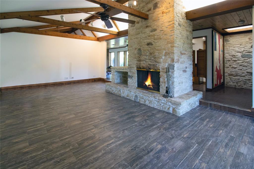 a view of an empty room with wooden floor fireplace and a window