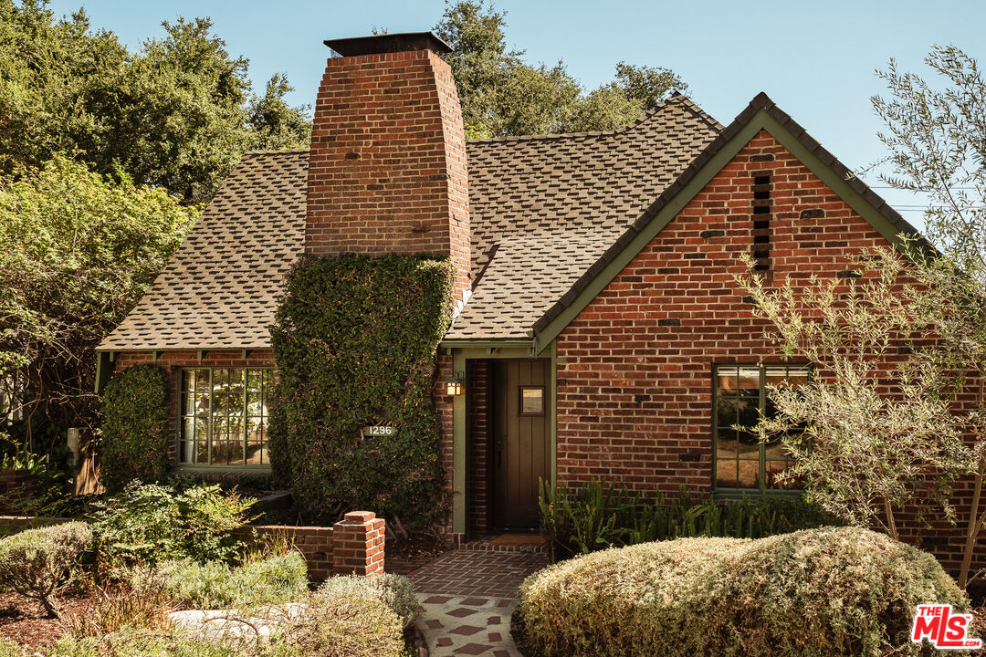 a view of a brick house with a small yard and wooden fence