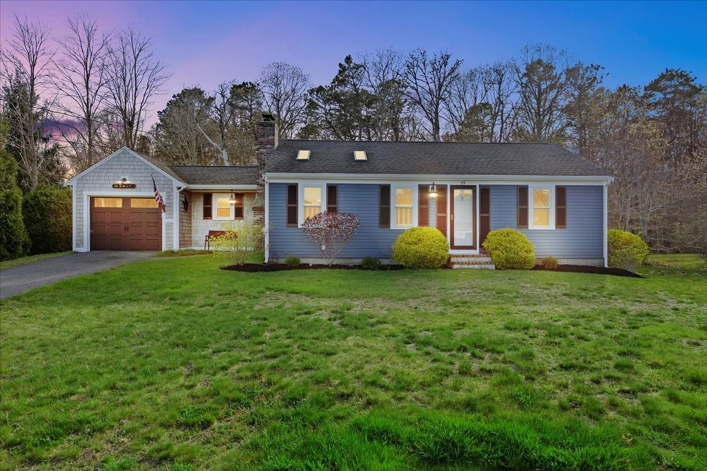 a front view of house with yard and trees in the background