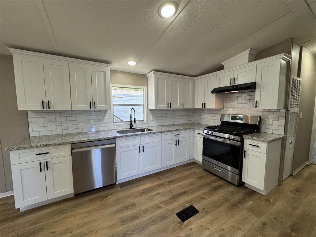 a kitchen with granite countertop a refrigerator stove top oven and sink