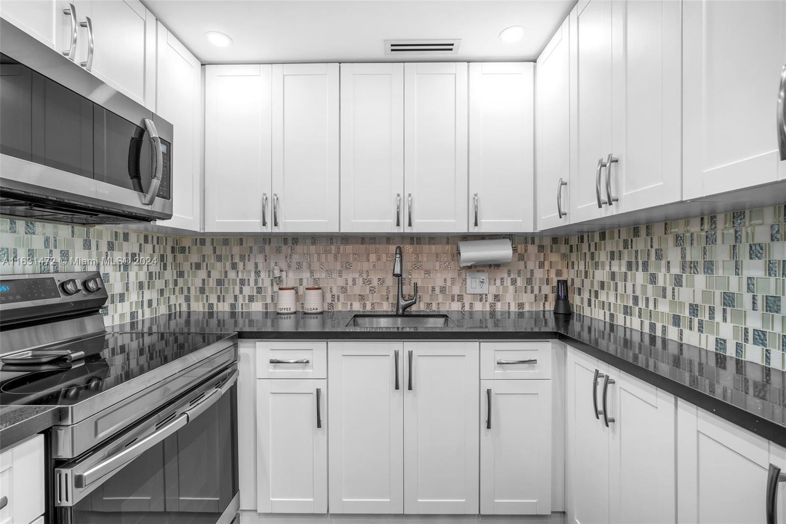 a kitchen with granite countertop white cabinets and stainless steel appliances