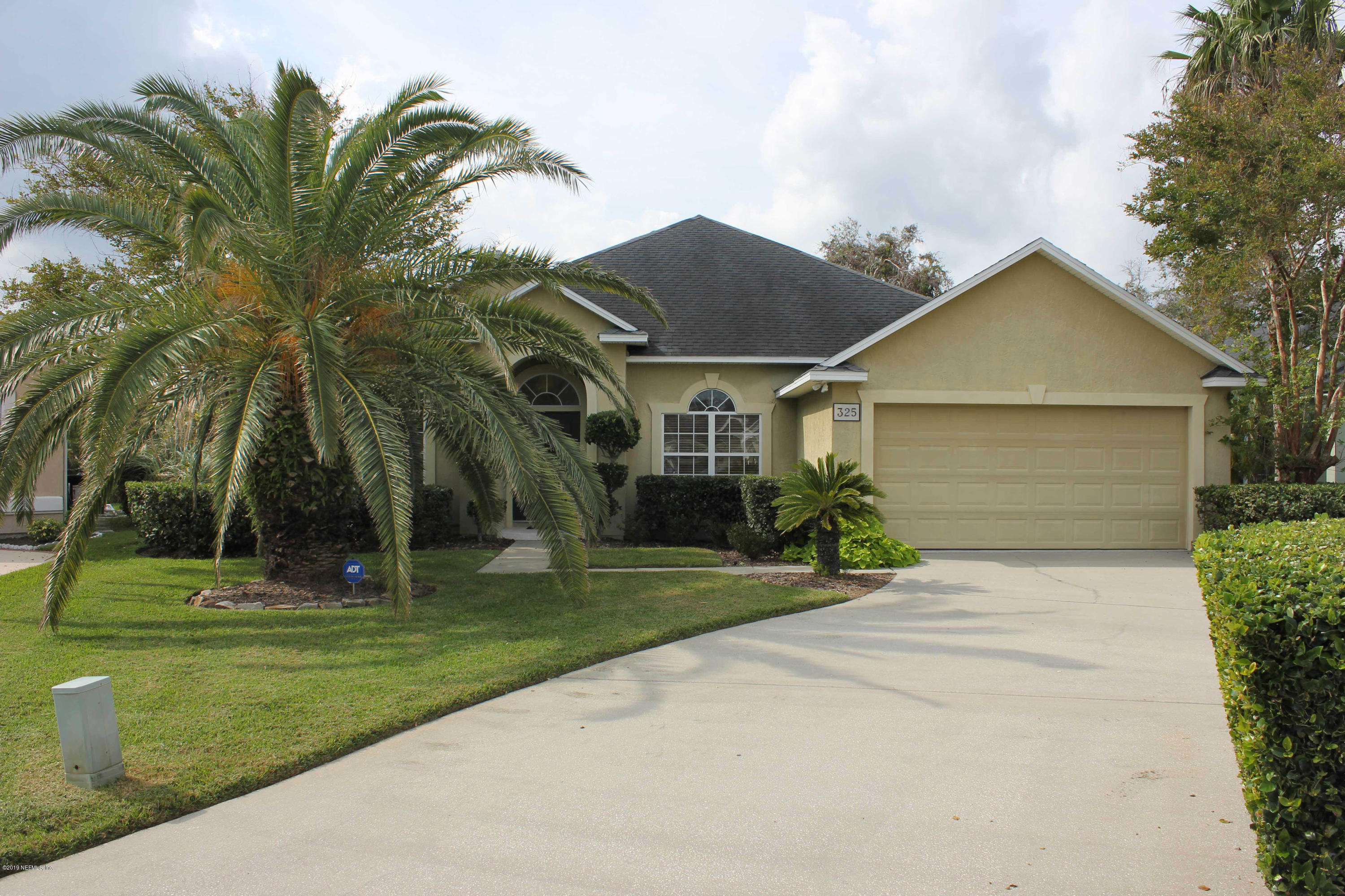 a view of a house with a yard and palm trees