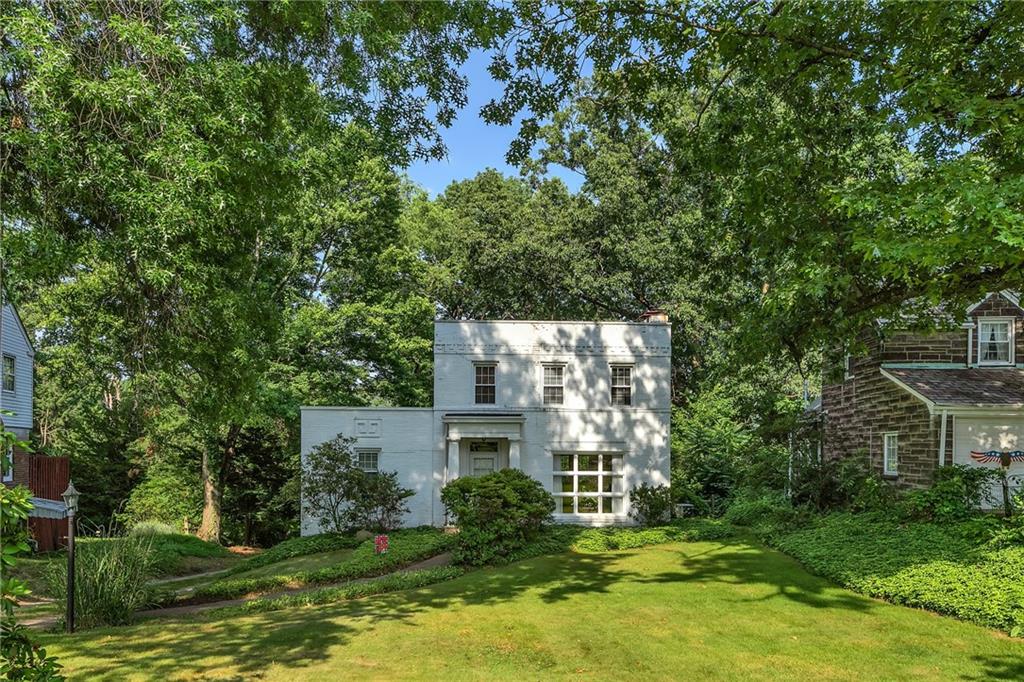 a view of a house with a big yard plants and large trees