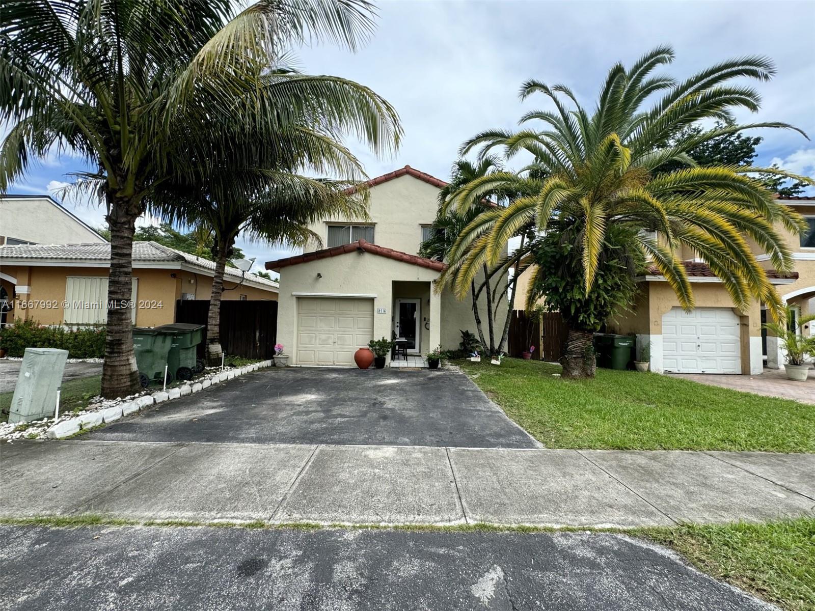 a view of a house with a yard and coconut trees