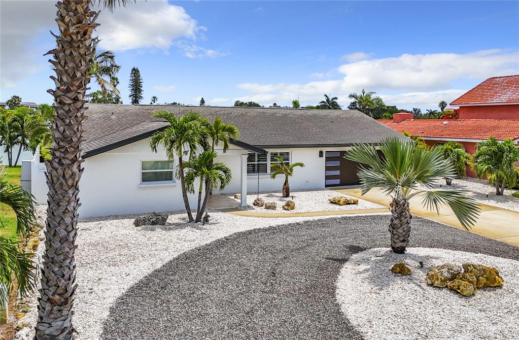 a palm tree sitting in front of a house with yard