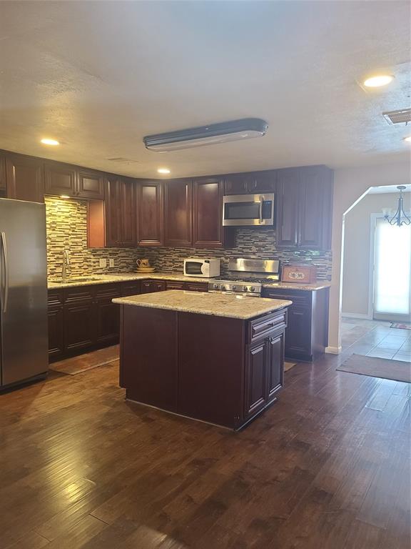 a kitchen with stainless steel appliances granite countertop a stove a sink and a refrigerator