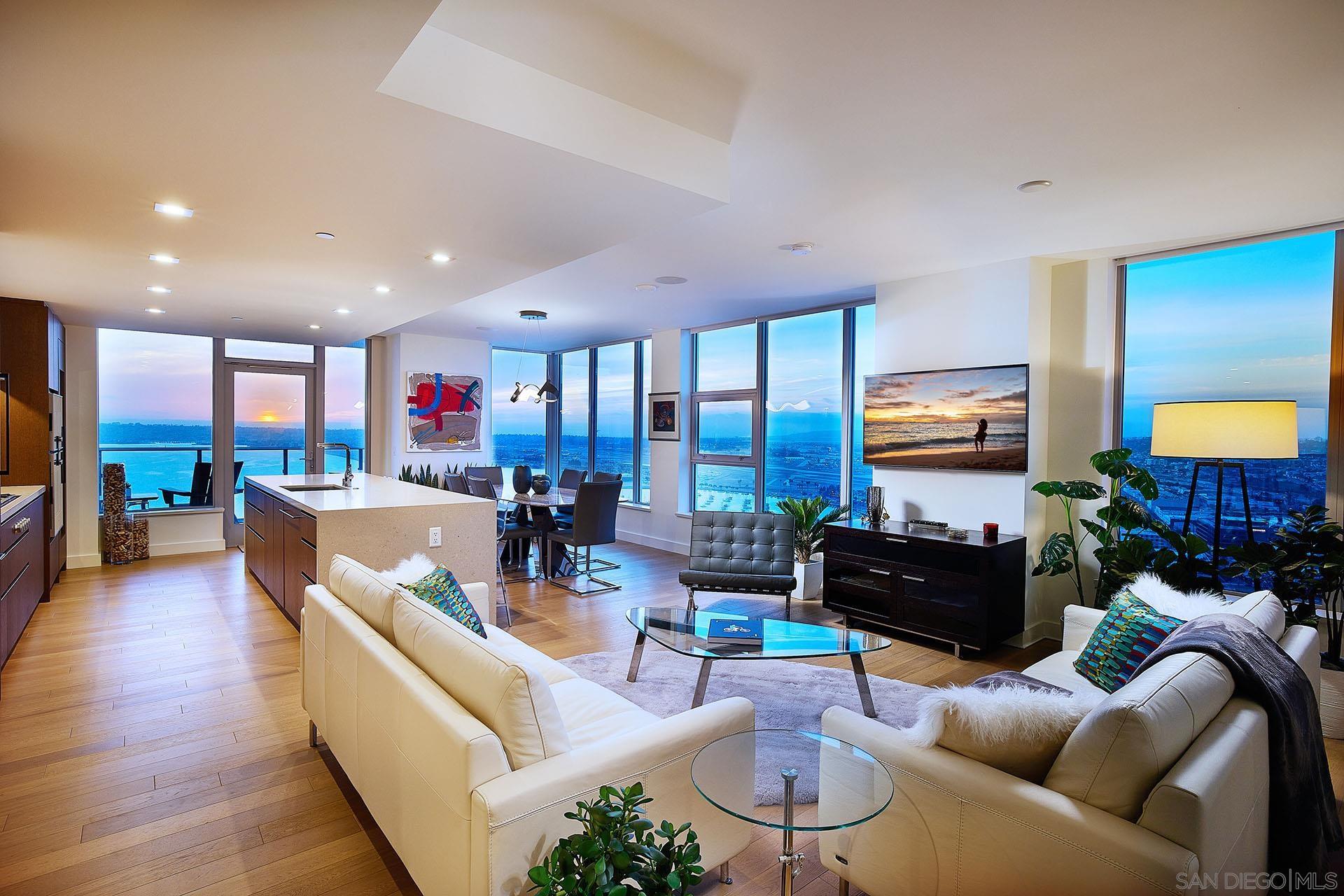 a living room with furniture kitchen view and a wooden floor