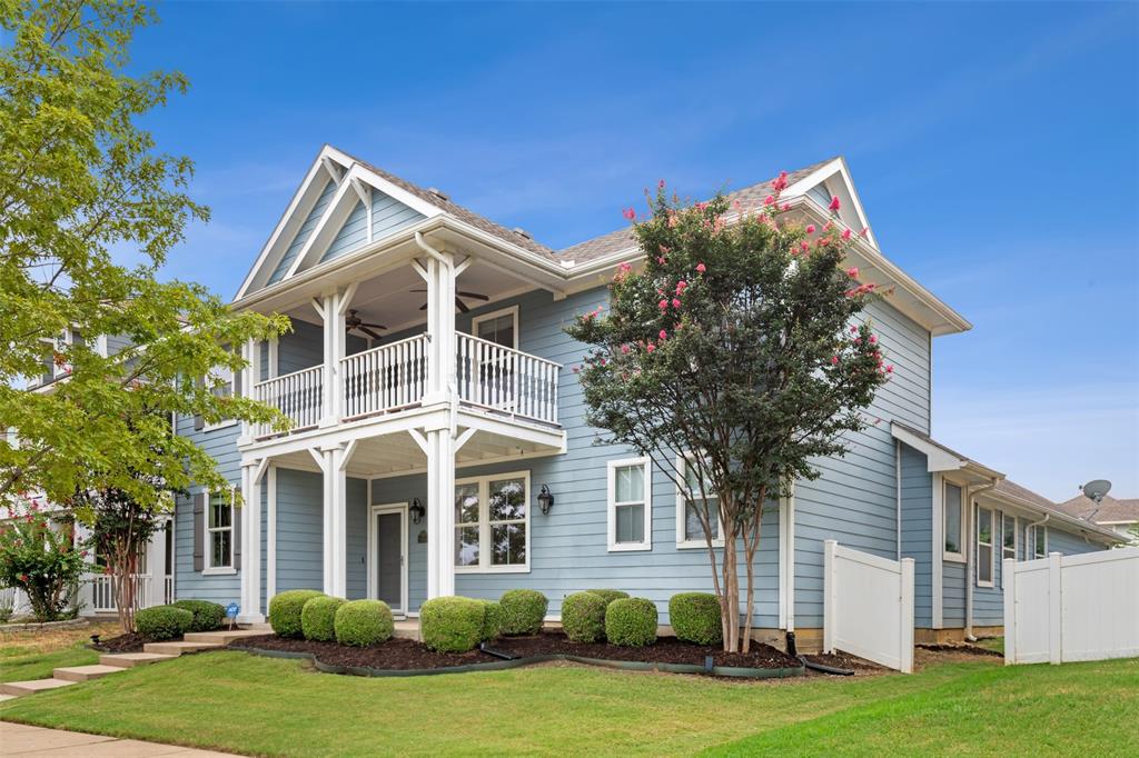 Gorgeous view of front of house with a balcony and well kept front lawn