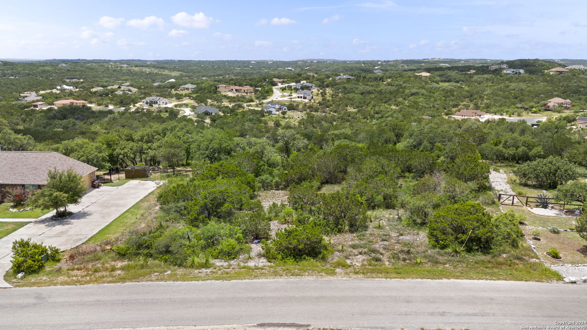 an aerial view of residential houses with outdoor space and trees