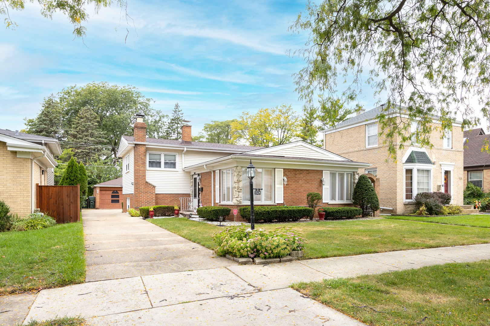 a front view of a house with a garden and trees