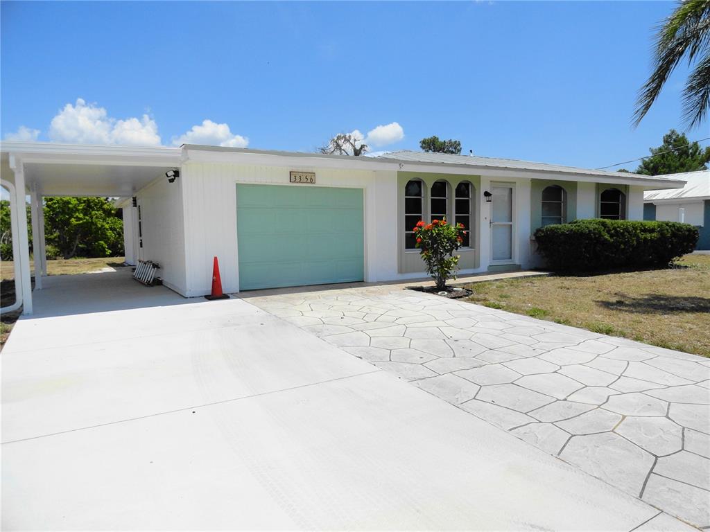 Front yard with large driveway and extra parking/storage under the covered area to the left of garage.  