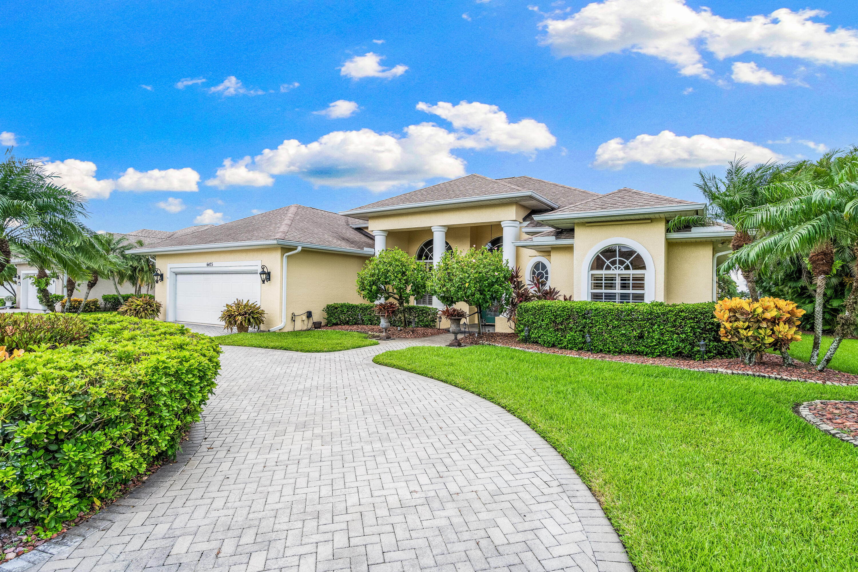 a front view of a house with a yard and potted plants