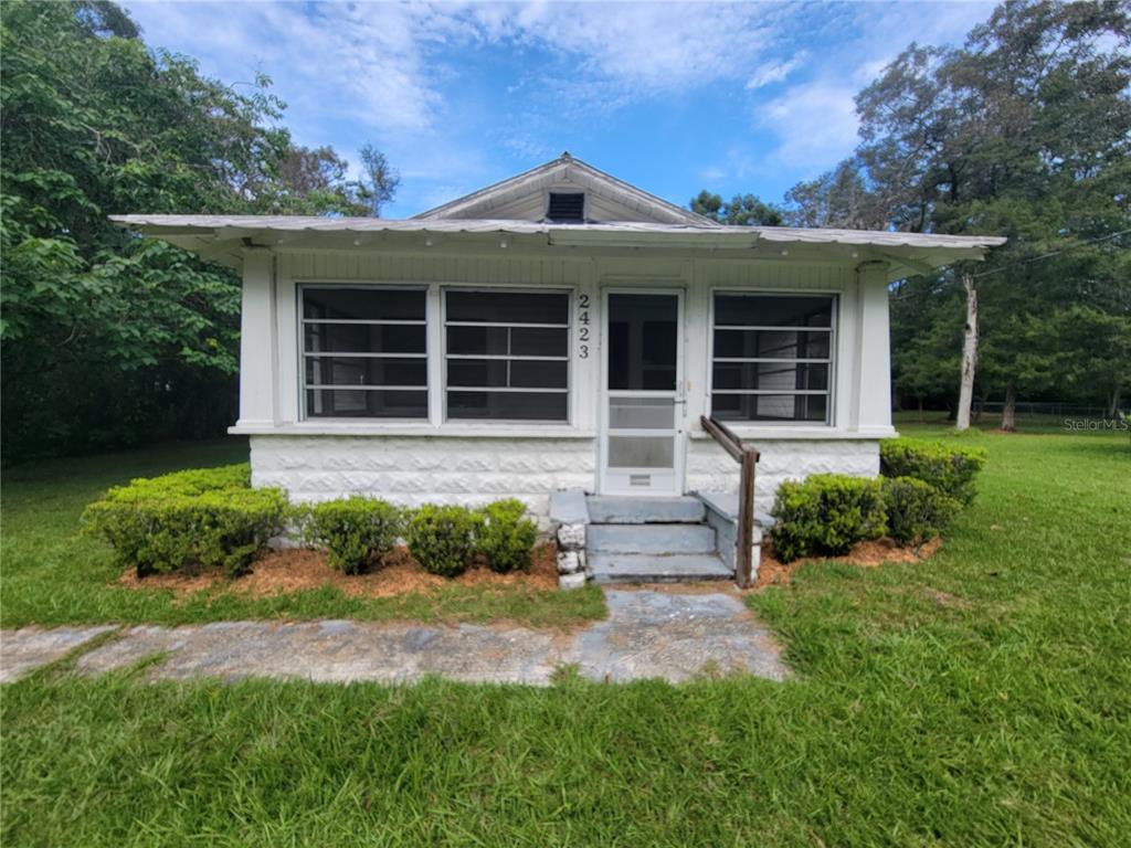 a front view of a house with a yard and potted plants