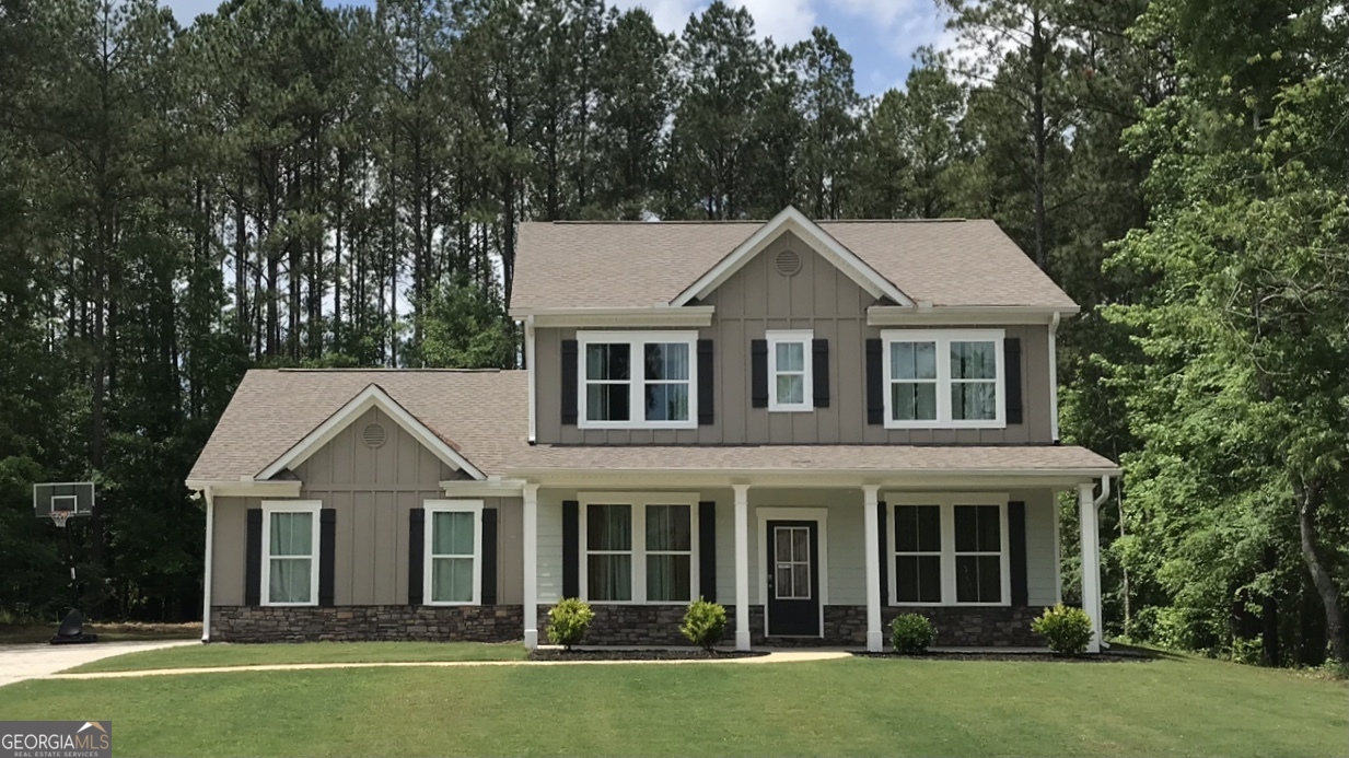 a front view of a house with a garden and trees