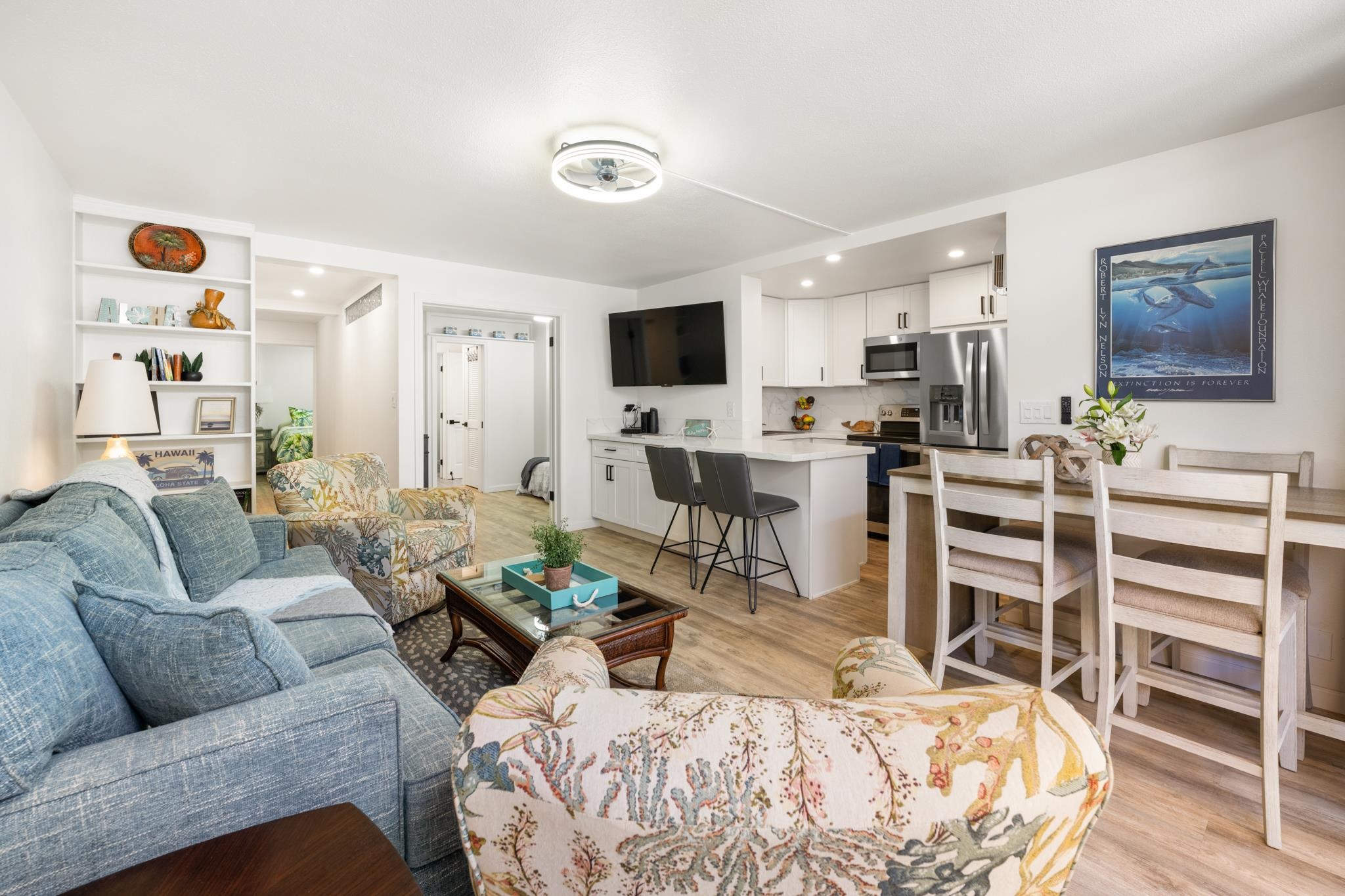 a living room with furniture kitchen view and a wooden floor