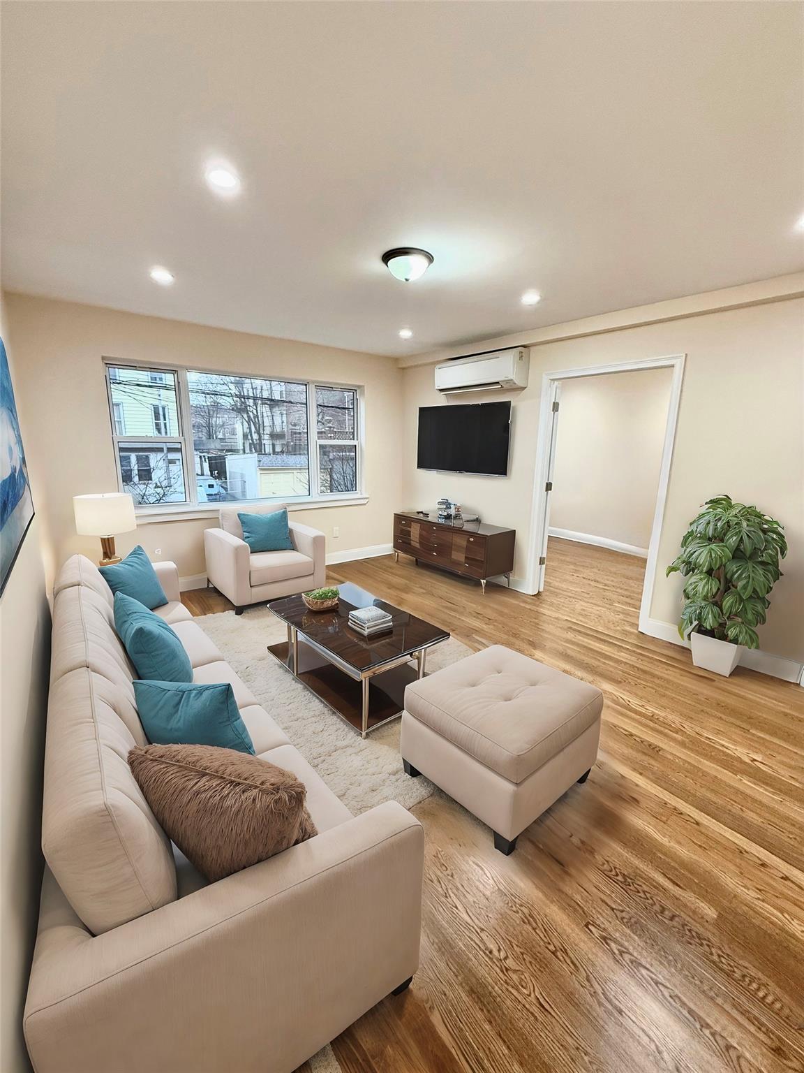 a living room with furniture flat screen tv and a large window