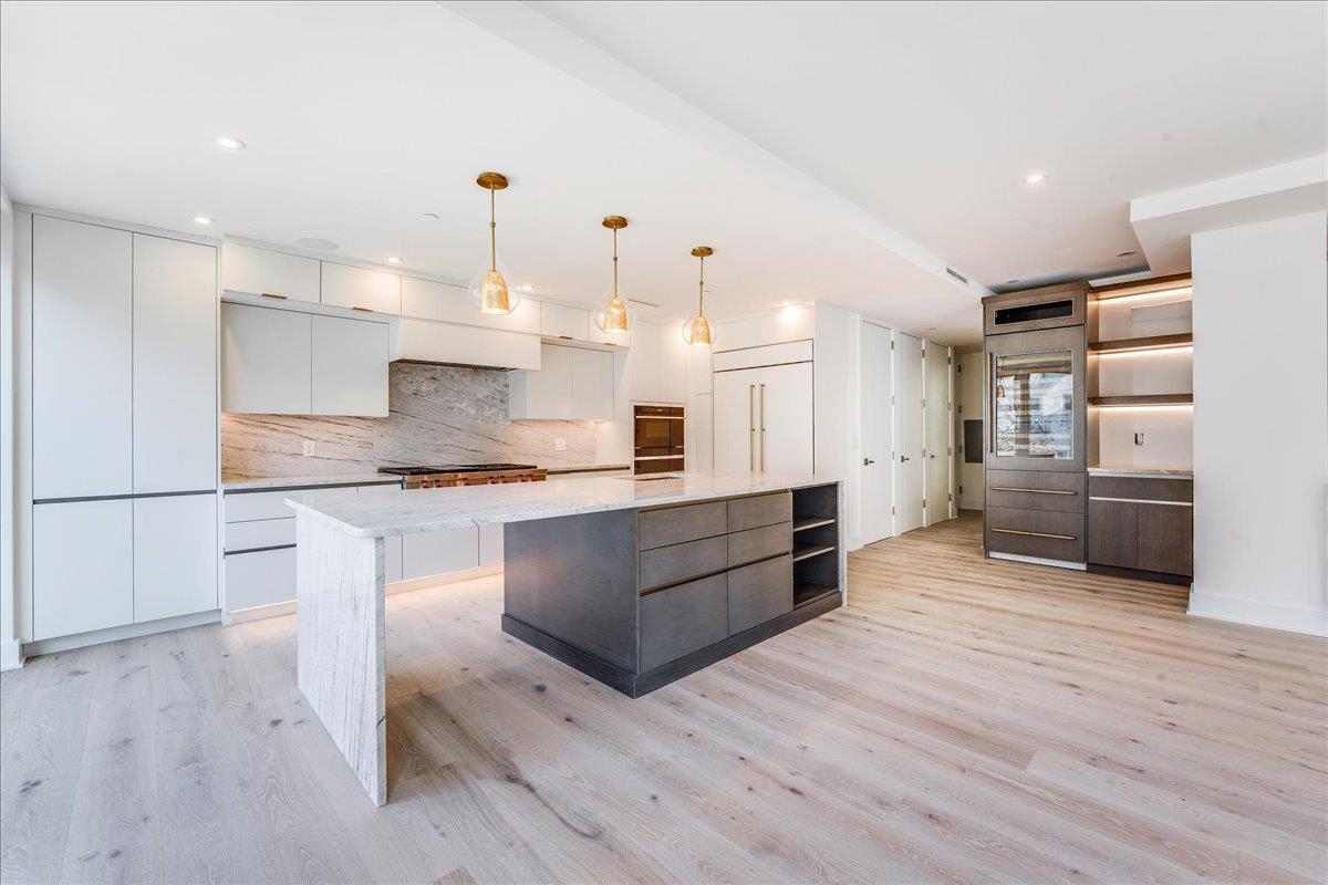 a large kitchen with stainless steel appliances kitchen island granite countertop a large counter top and white cabinets