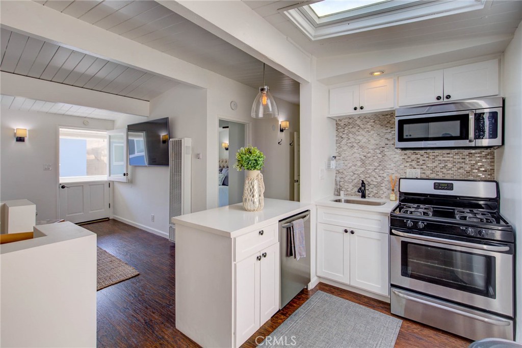 a kitchen with cabinets stainless steel appliances and wooden floor