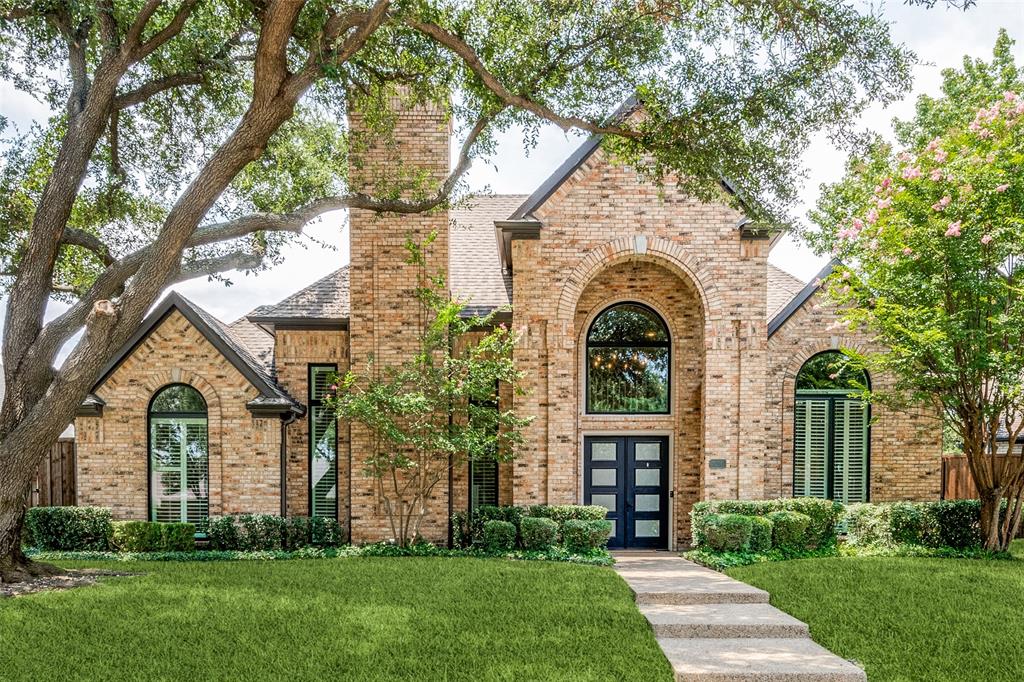 a view of a house with brick walls and a large tree