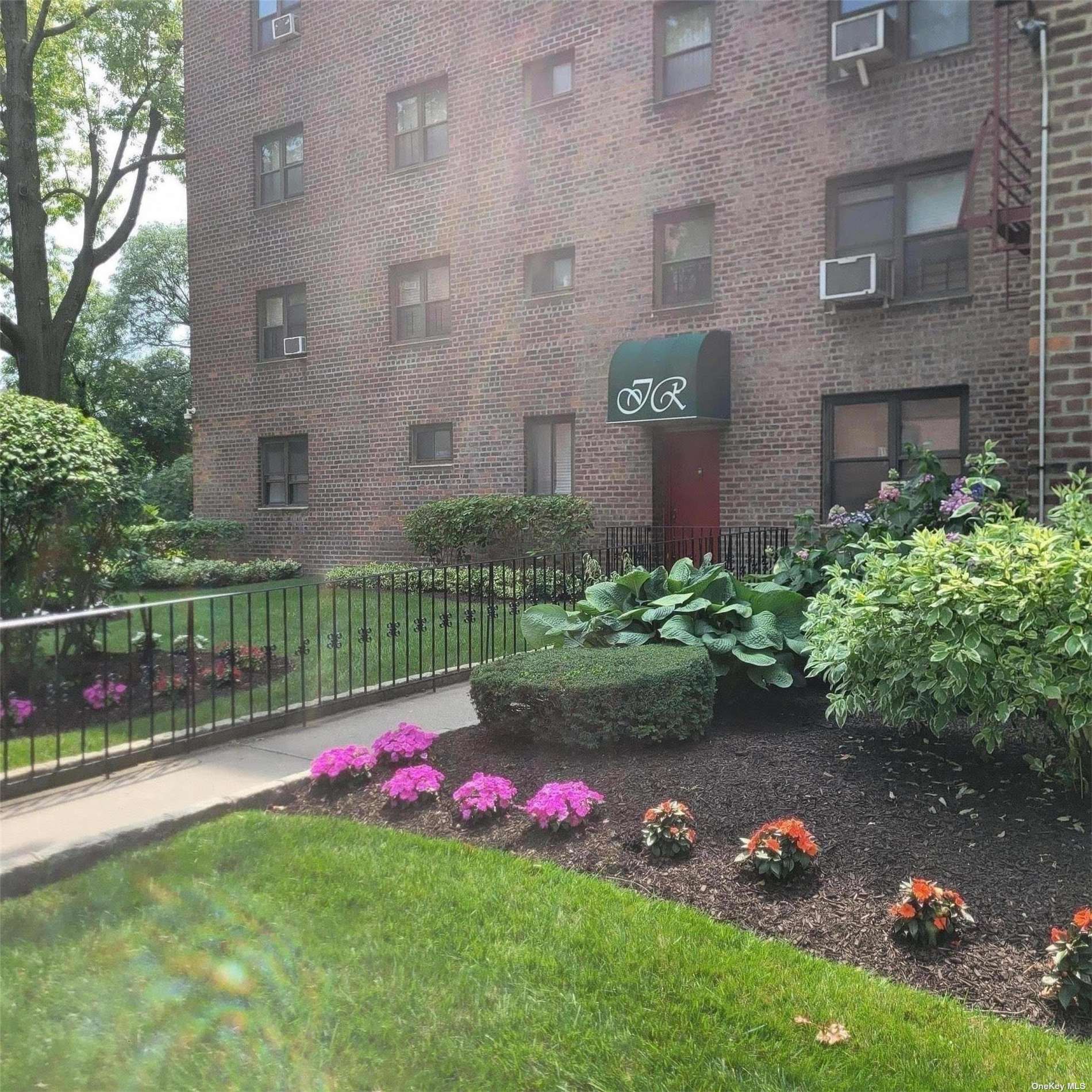 a view of a brick house with a yard and a garden